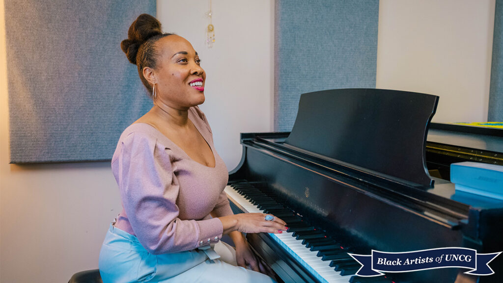 UNCG visiting professor of voice Janinah Burnett sits at a piano