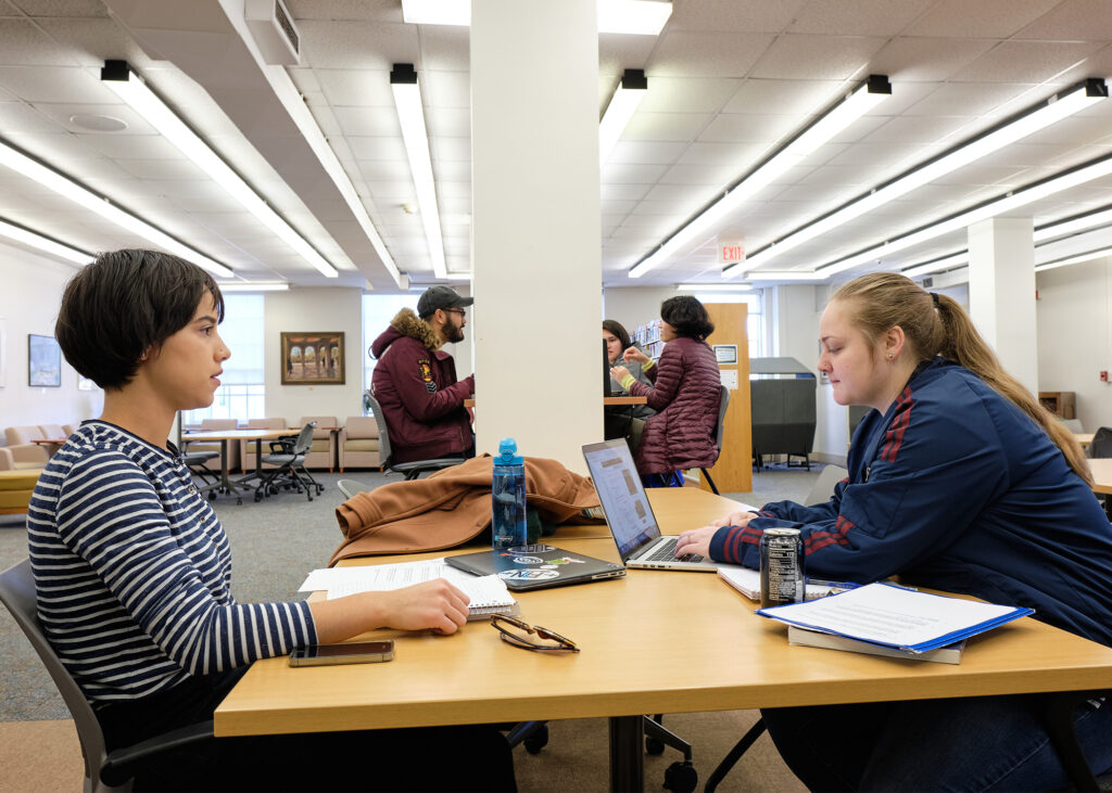 Students studying at tables and desks in the Jackson Library.