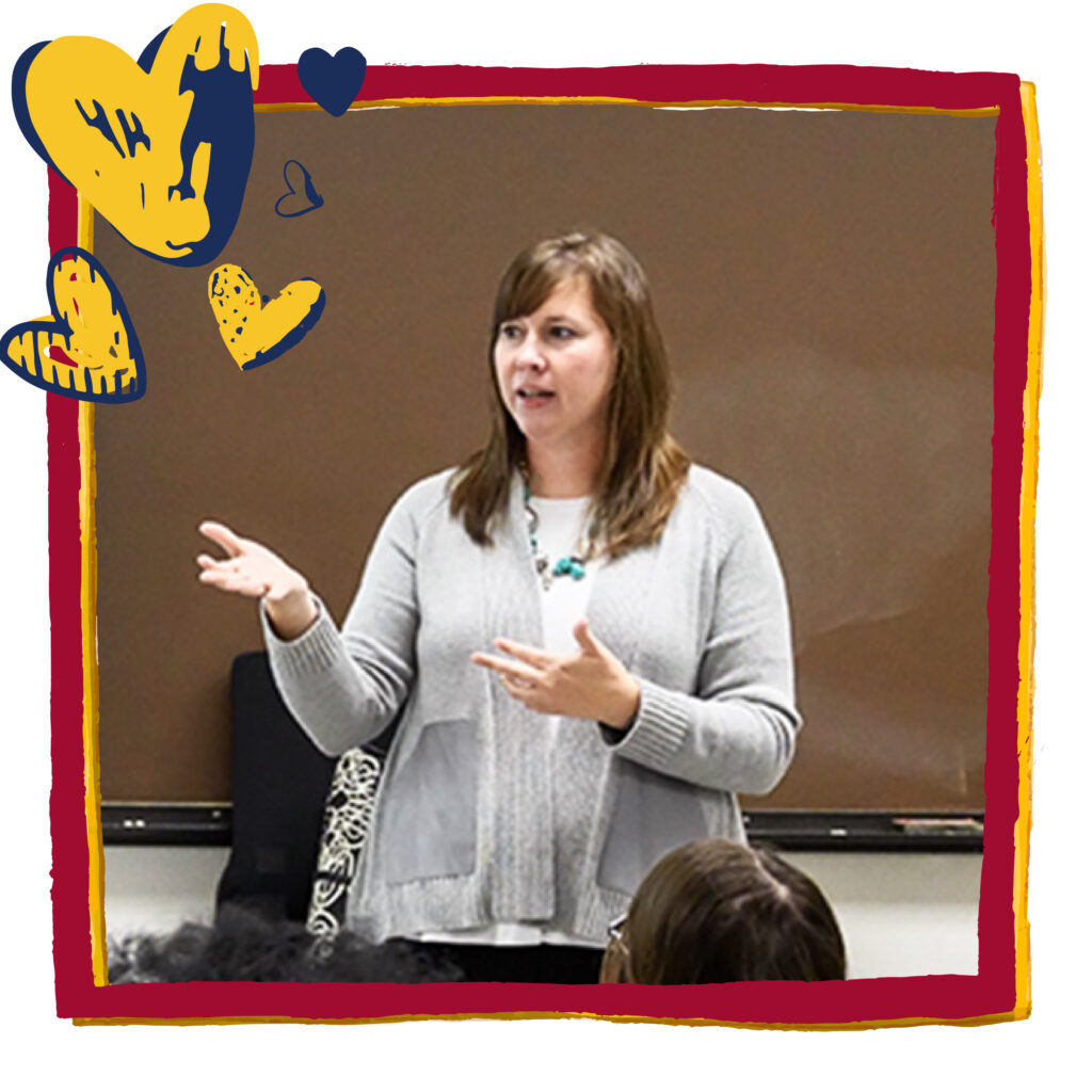 Teacher in front of a classroom talks with her hands. Red frame and blue and gold heart graphics have been added to headshot.