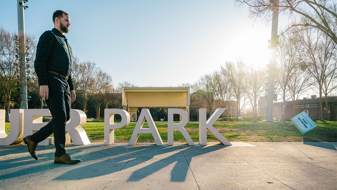 A man walks in front of a sign that states Park.