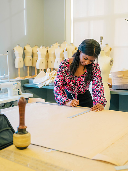 UNCG consumer, apparel, and retail studies student Tues-Dé Whethers makes measurements for cloth.