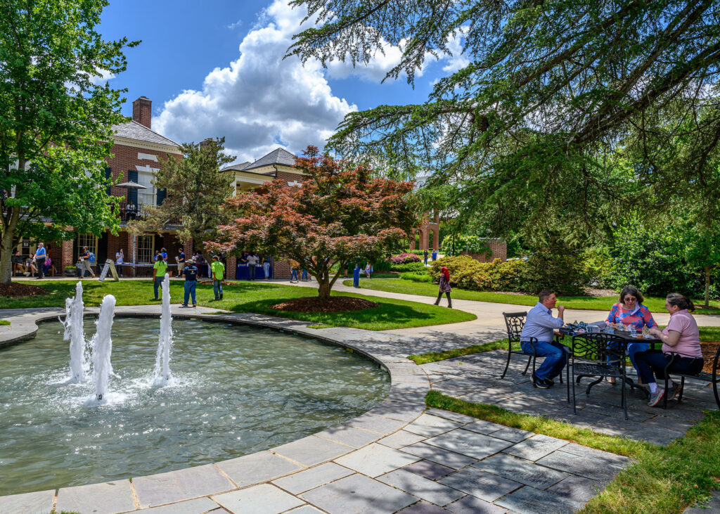 Fountains and gardens between EUC and Alumni House with tables and people having lunch.