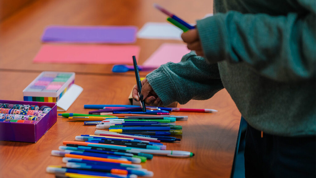 A UNCG student looks through a pile of pens on the table.
