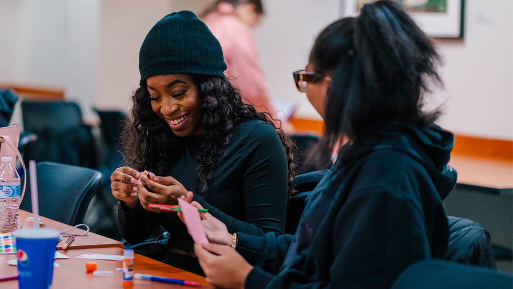 UNCG students talk and laugh while making valentines with the Letter Project.