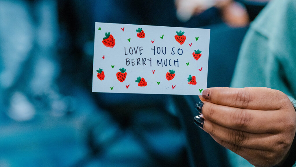 A UNCG student holds up a valentine card made by the Letter Project.