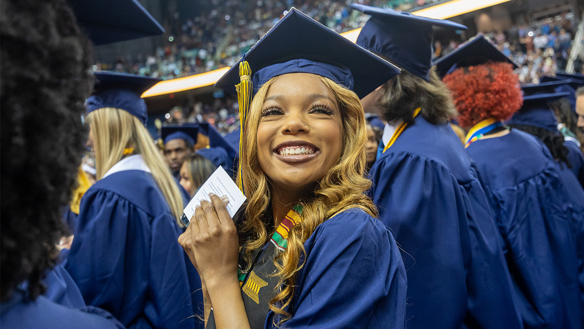 A UNCG graduating student smiles at Commencement.
