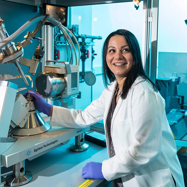 Woman in lab coat works with technology in a Joint School of Nanoscience and Nanotechnology lab.