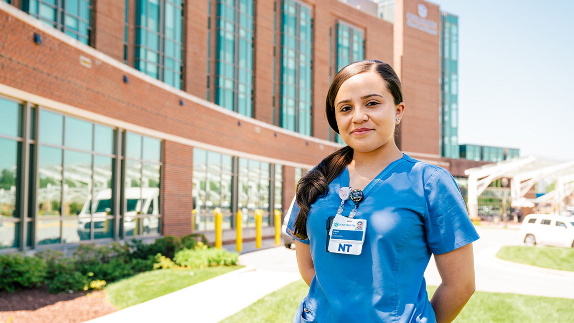 Young nurse stands in front of Moses Cone Hospital.
