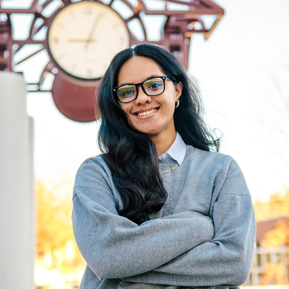 Student poses in front of the UNCG clock tower.