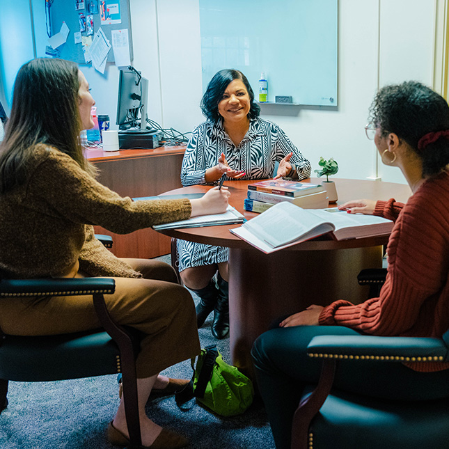 A teacher advises two students in her office.