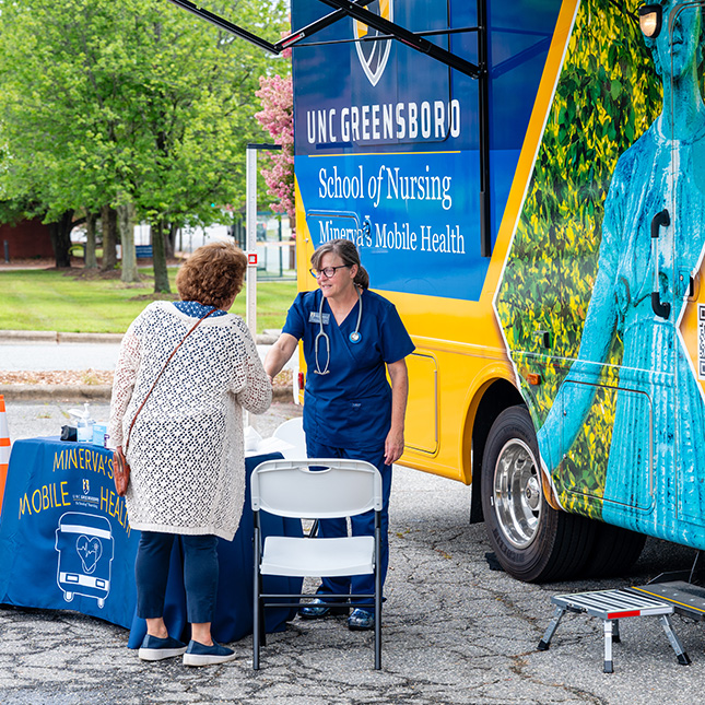 A nurse greets a patient outside of Minerva's Mobile Health Unit. The patient is
