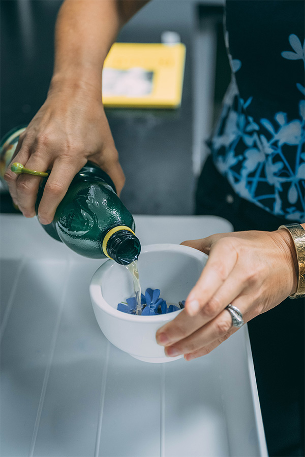 UNCG photography associate professor Leah Sobsey pours lemon juice onto flowers inside a mortar.
