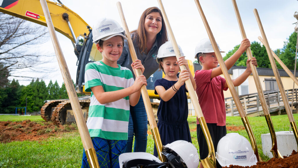 Dr. Whitney Oakley stands with children at a groundbreaking site.