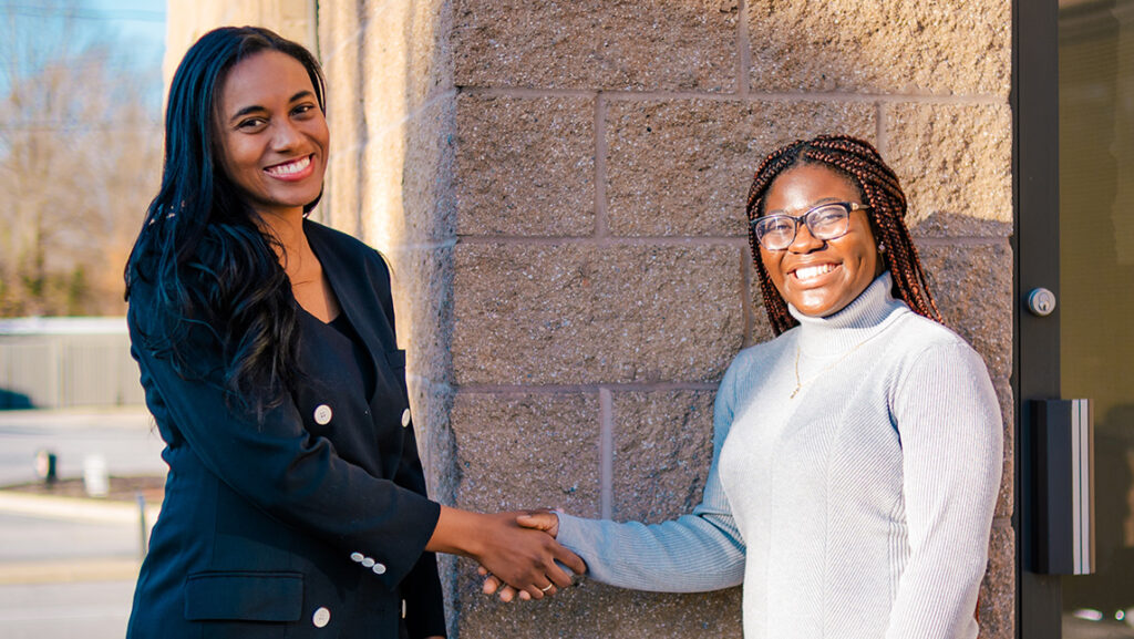 Doctoral student Youselene Beauplan shakes hands with Dr. Jocelyn Smith Lee at UNCG.