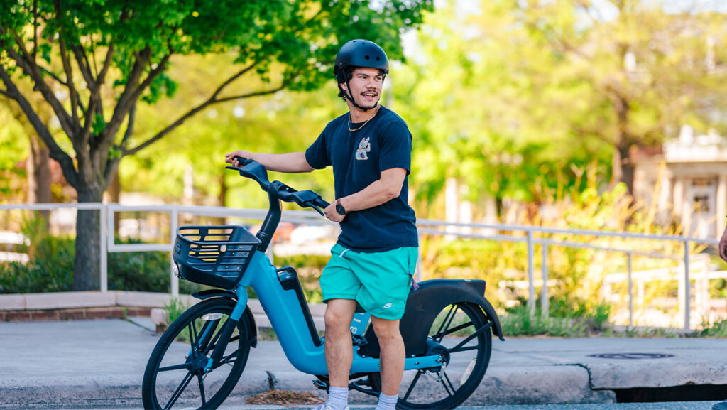 Student stands with blue bird bike