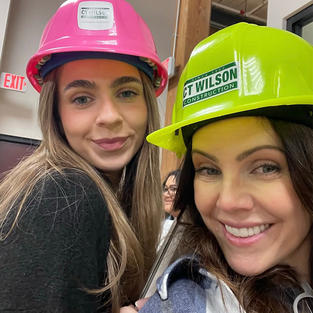 Two women take a selfie in hard hats.