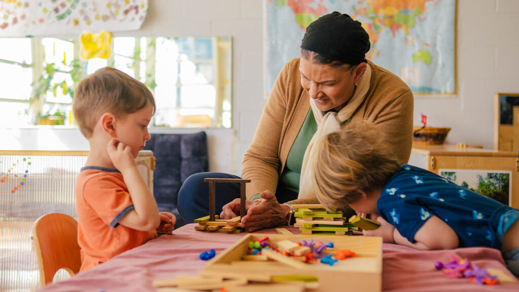 A UNCG Child Care Education Program staff member works with two children
