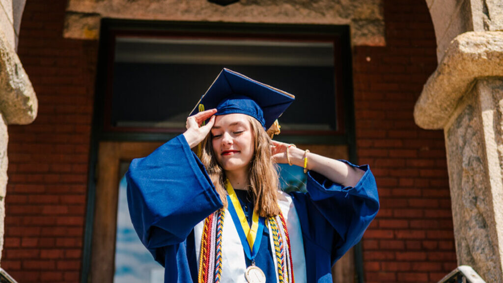 Hannah Ward poses in a cap and gown out side of the Lloyd International Honors College