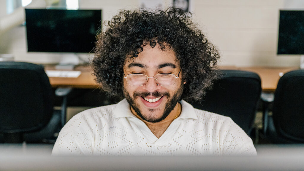 UNCG student smiles while working on a computer