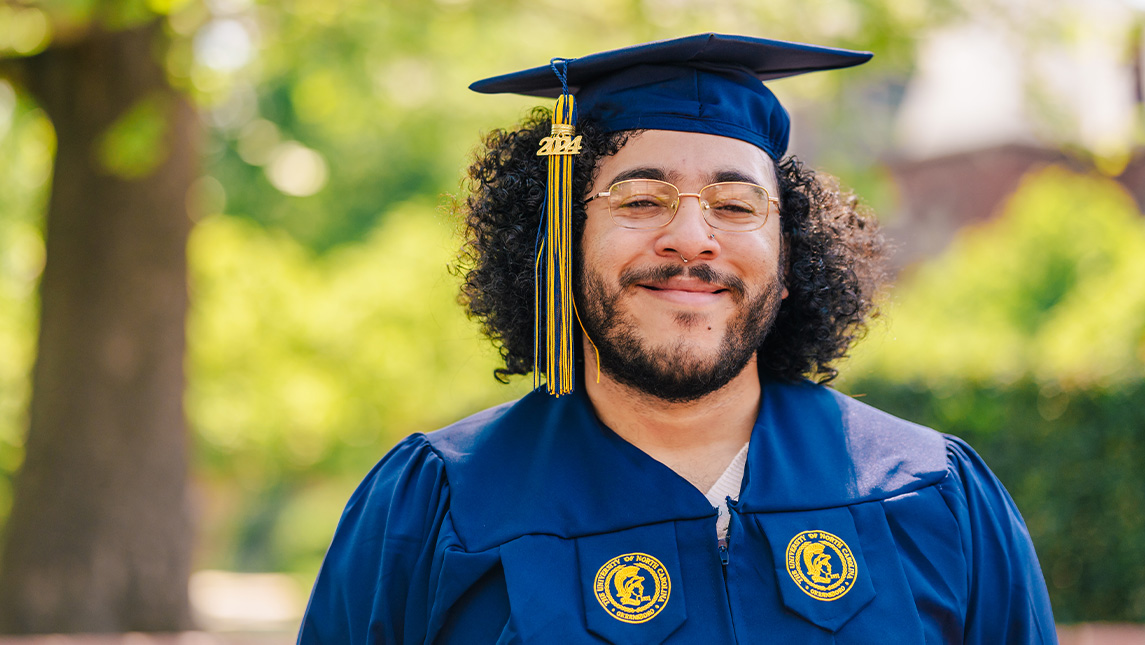 UNCG student smiles in cap and gown