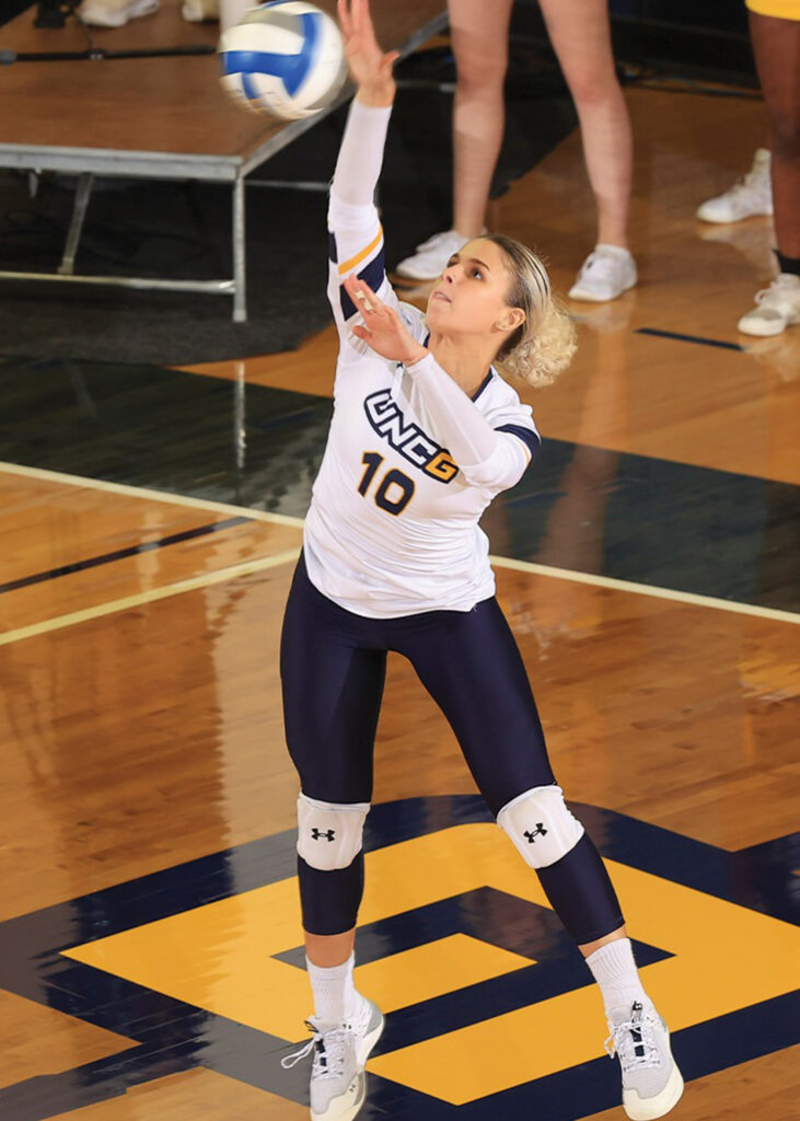UNCG women's volleyball player stretches to hit the ball.