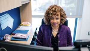 Debra Neblett sitting at her desk looking at her computer in the UNCG School of Nursing.