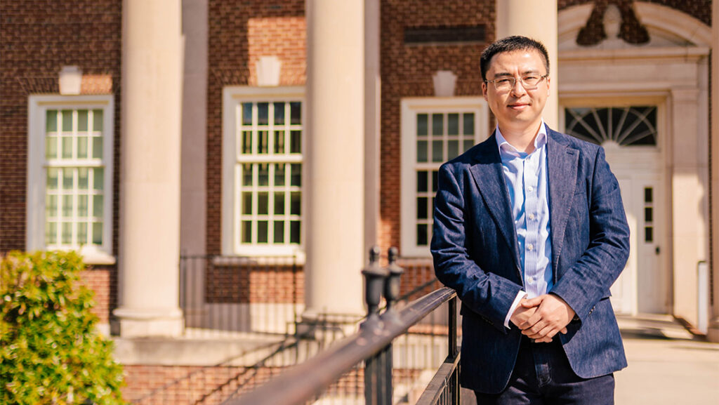 A headshot of a professor with a building behind him.