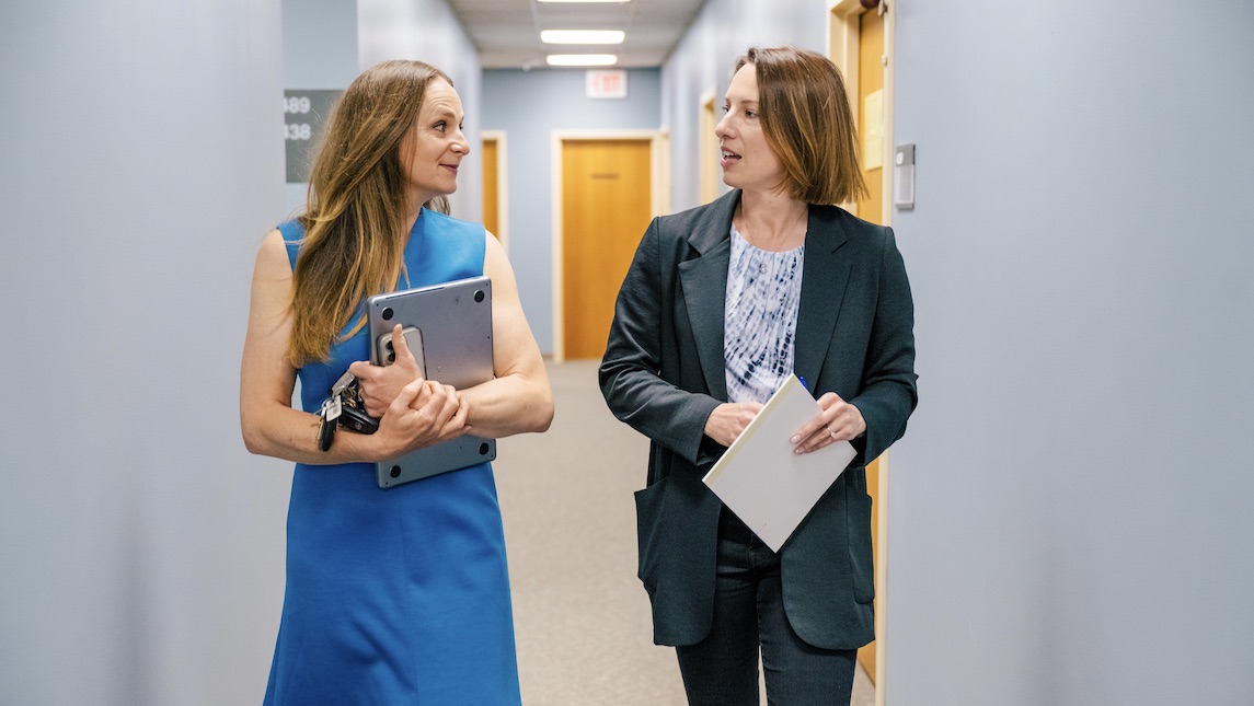 Brianna walking down the hallway at UNCG's BSBE school talking with a mentor.