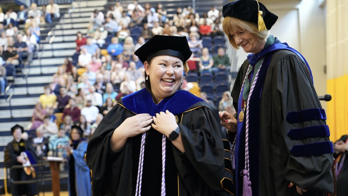Laura Kennedy Malone at UNCG graduation ceremony with a student.