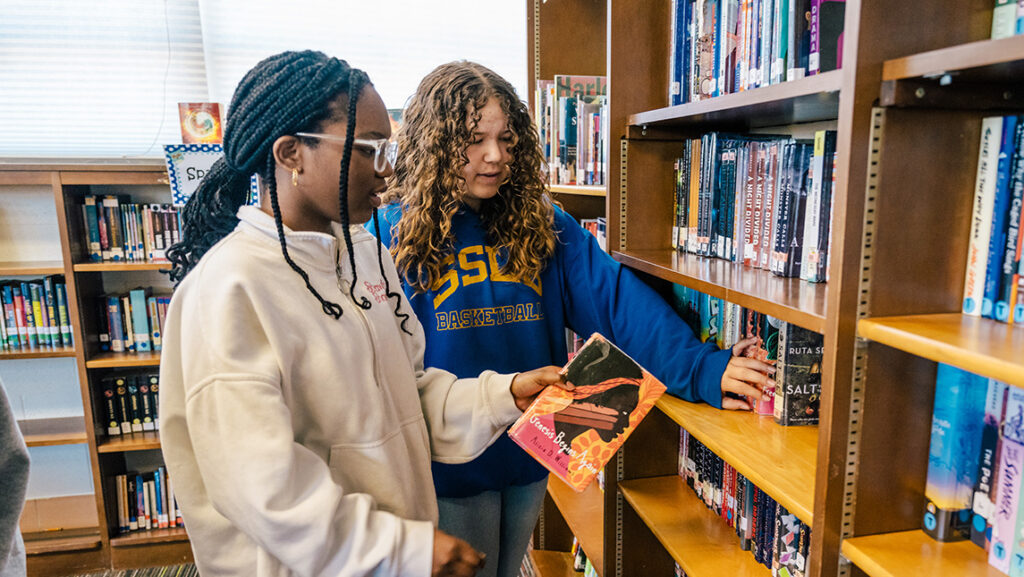 Two middle school students shelve library books.