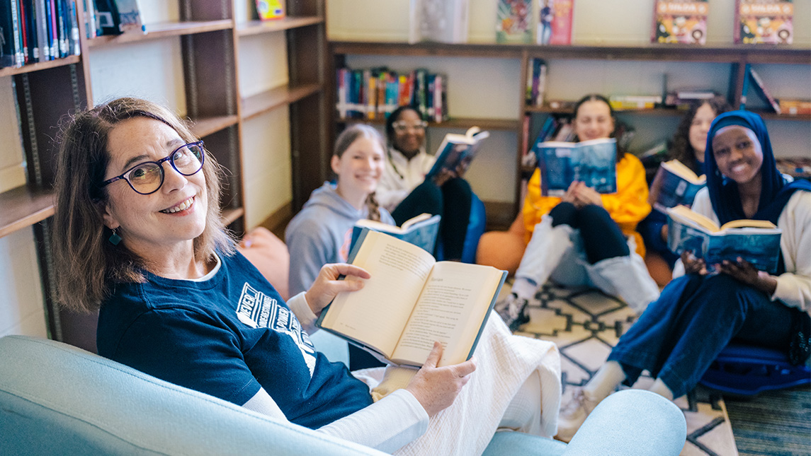 Dawn Shirk, a UNCG library alumna, sits in a circle with middle school students reading books.