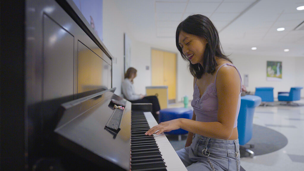 UNCG student Phoenyx Raiola plays piano in Moran Commons.