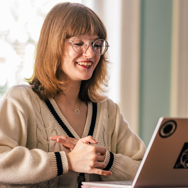 Student looks at a laptop and smiles. Student