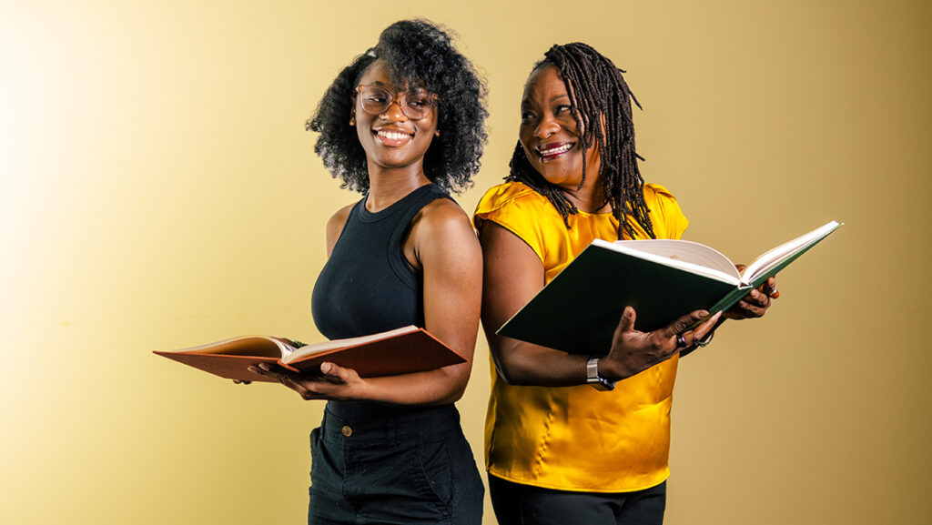 UNCG's Regina McCoy stands back to back with a student holding textbooks.