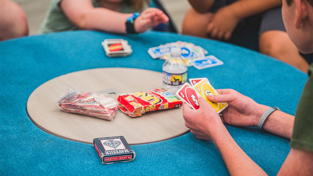 Close-up on students' hands as they deal UNO cards.