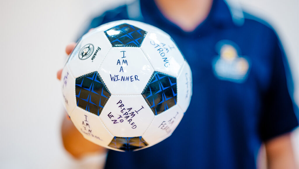 A student displays a soccer ball with inspirational statements.