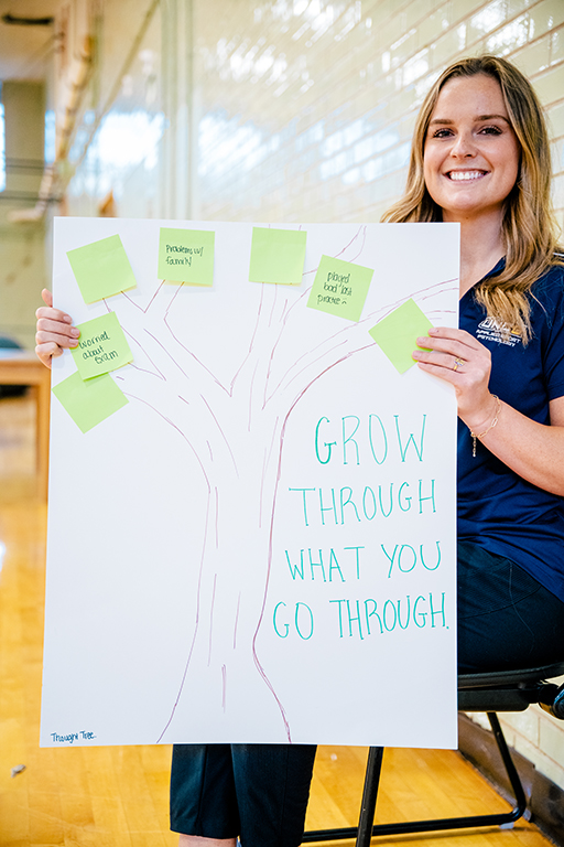 A student shows a poster board of a tree.