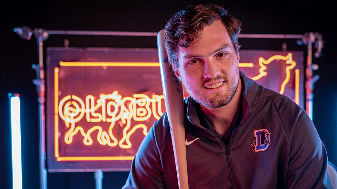 UNCG alum Keaton Haack holds a baseball bat and smiles