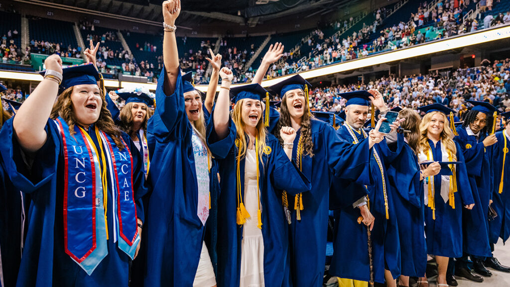Group of UNCG grads cheering at commencement.