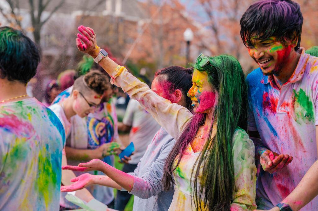 Students on UNCG campus with paint all over their clothes & faces.