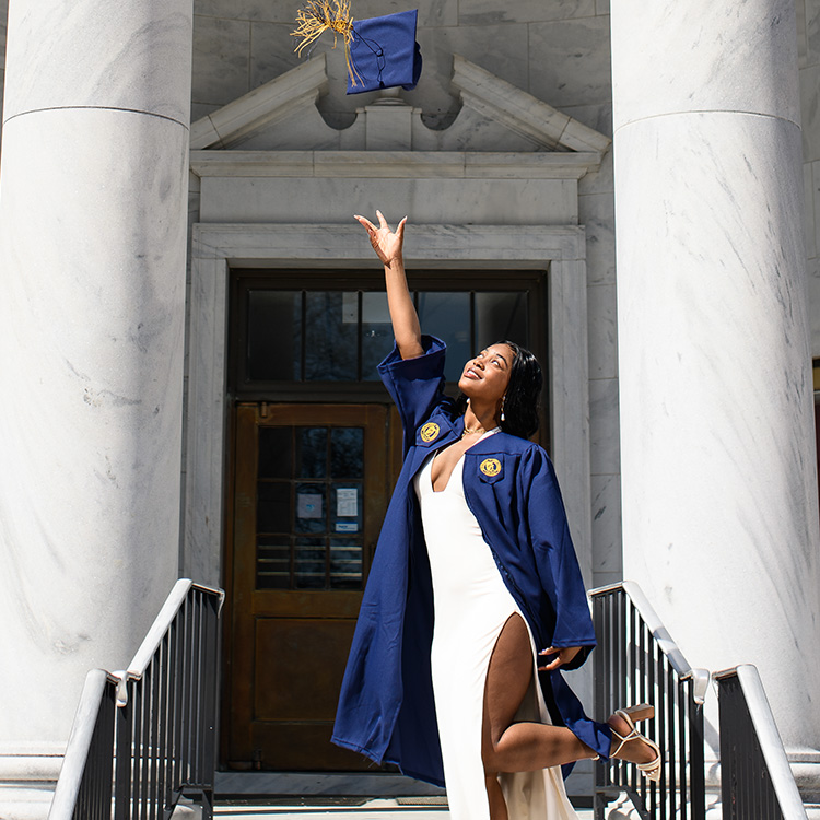 UNCG 2024 grad Trinity Shealy tosses her graduation cap while wearing her gown.