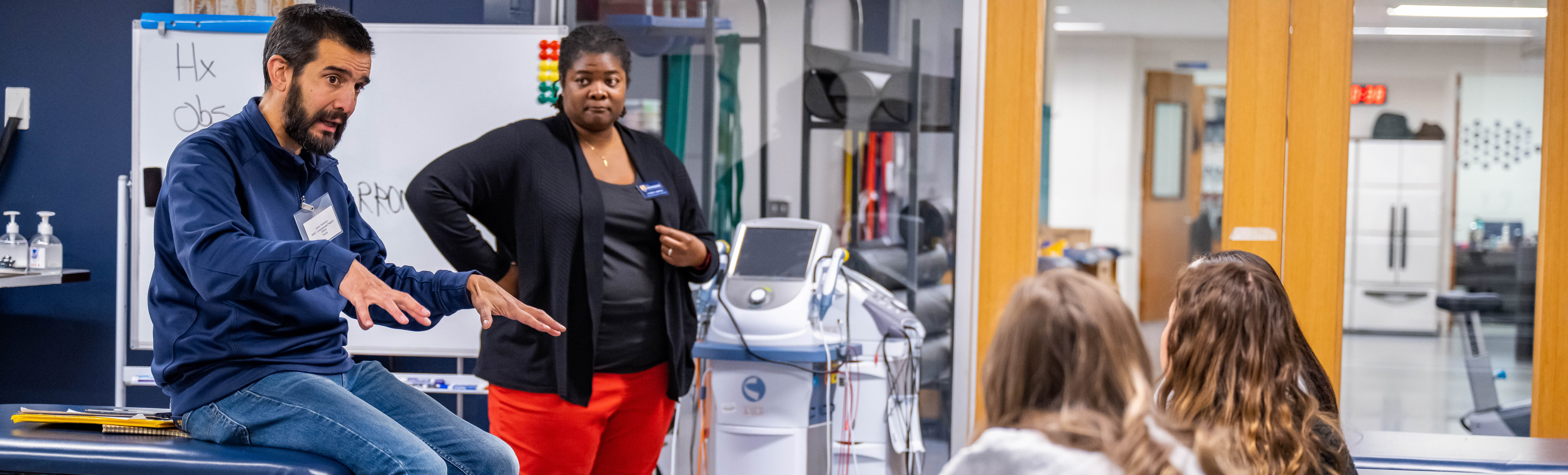 Kinesiology male and female faculty talk to students.