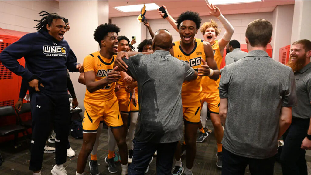 UNCG basketball students celebrate in the locker room after a win.