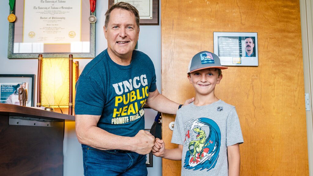 UNCG professor Mike Perka gives a boy a fist bump.