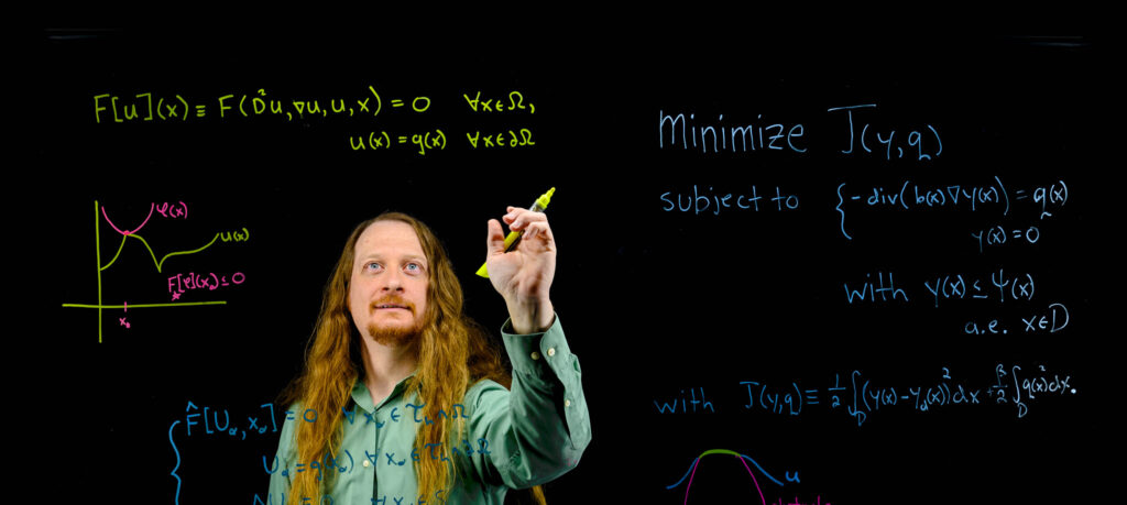 a math and stats instructor writing on a blackboard during a lesson.