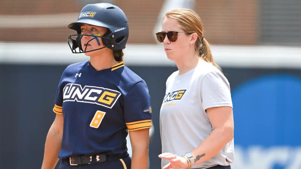 Ally Davis walks beside a UNCG softball player.