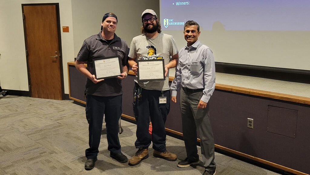 UNCG facilities associate vice chancellor Sameer Kapileshwari gives awards to Russell and Munday.