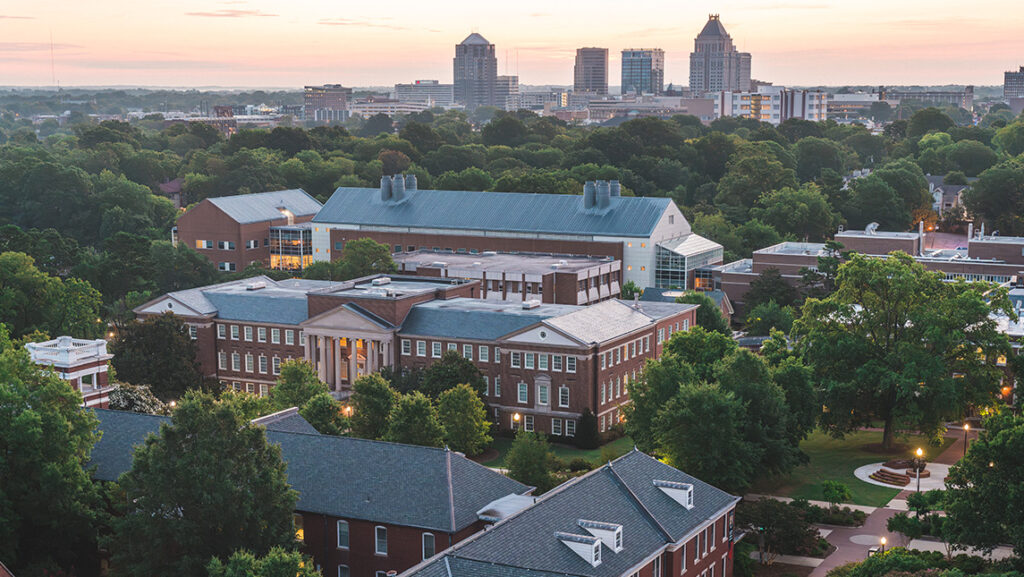 Arial view of UNCG campus with Greensboro skyline in the distance.
