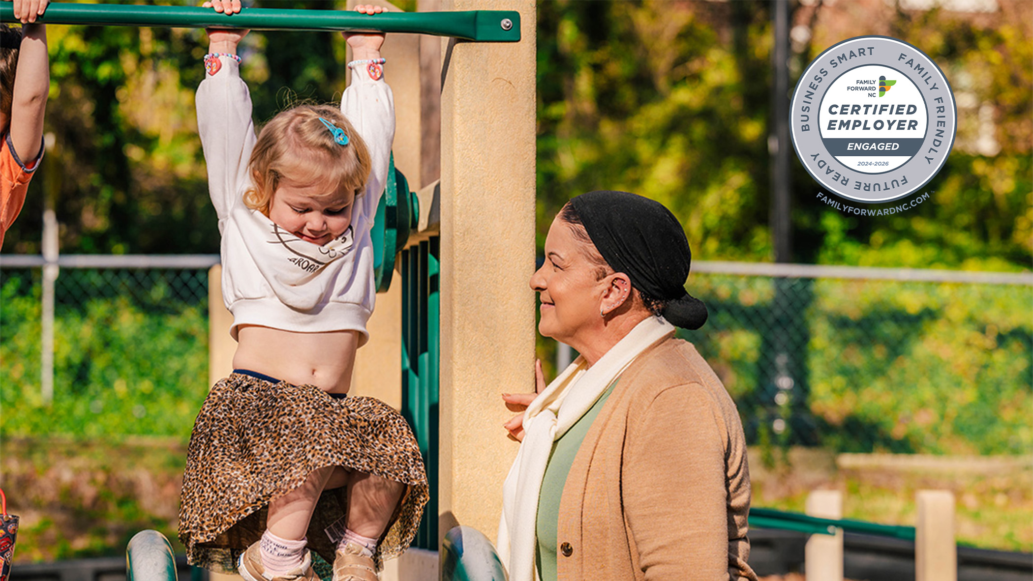 A UNCG employee watches a girl on the playground slide.