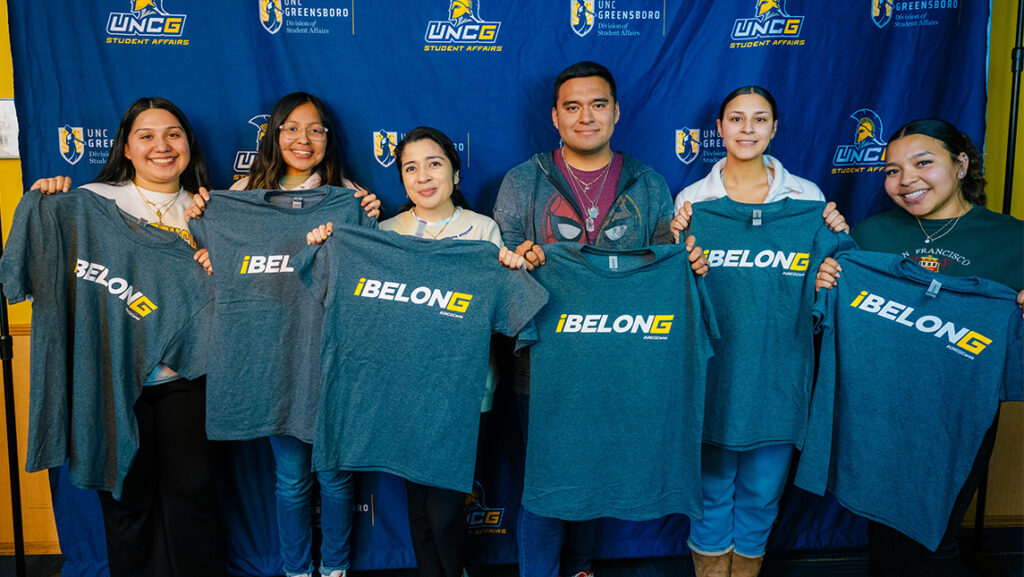 UNCG students hold up shirts with "I Belong" written on the front.